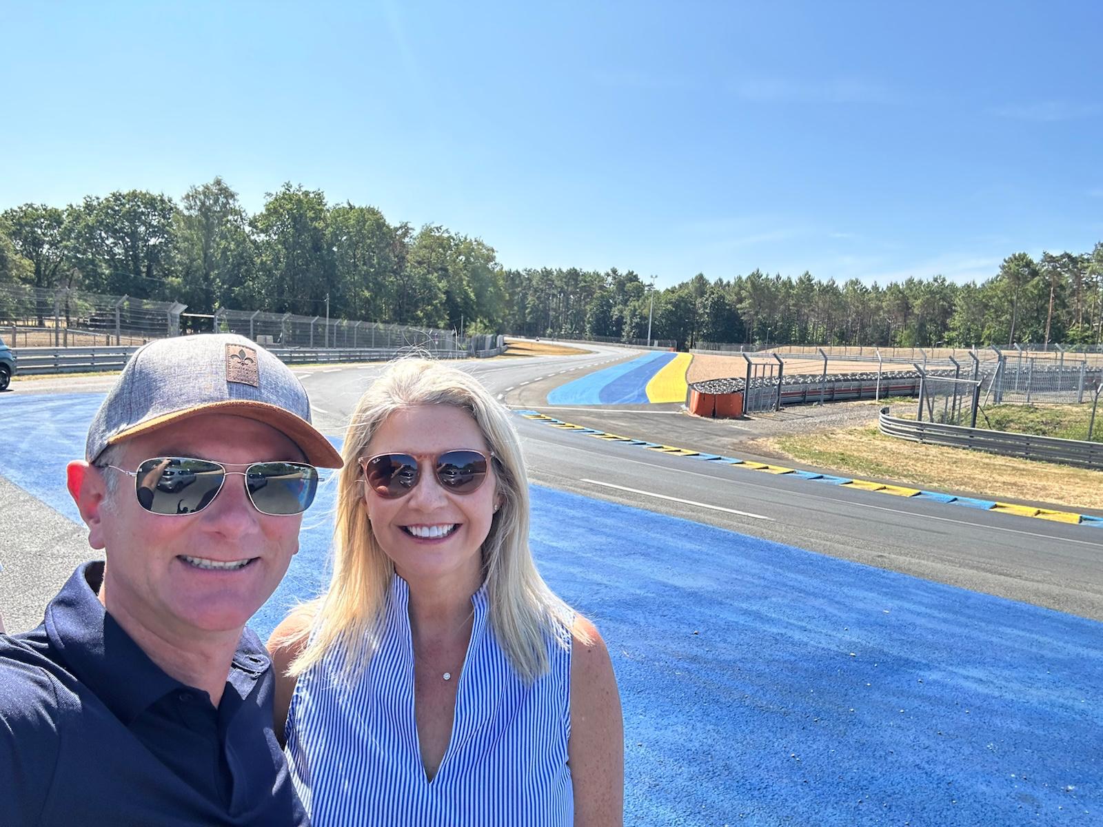 Harry and Laurie Hollander smiling together beside a racetrack